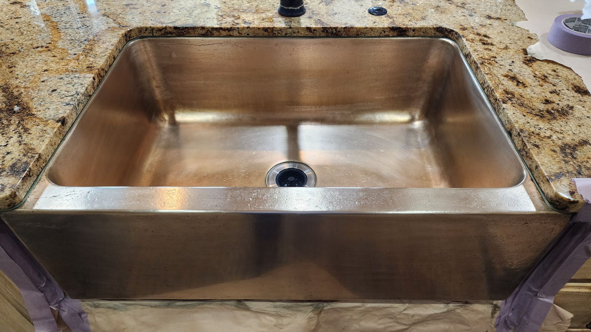 Stainless steel kitchen sink set into a stone countertop, viewed from above.