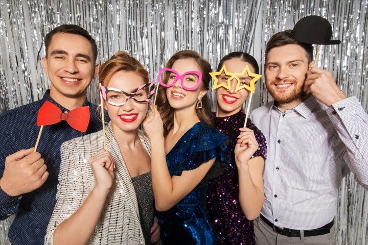 Colleagues posing with fun props in a silver sequin photo booth.