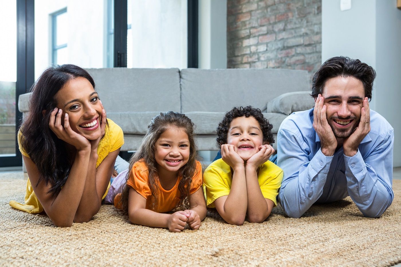 A family is laying on the floor in a living room.
