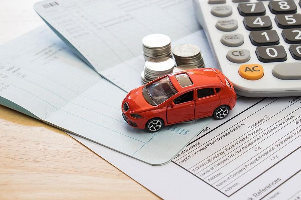 A toy car is sitting next to a calculator and stacks of coins.