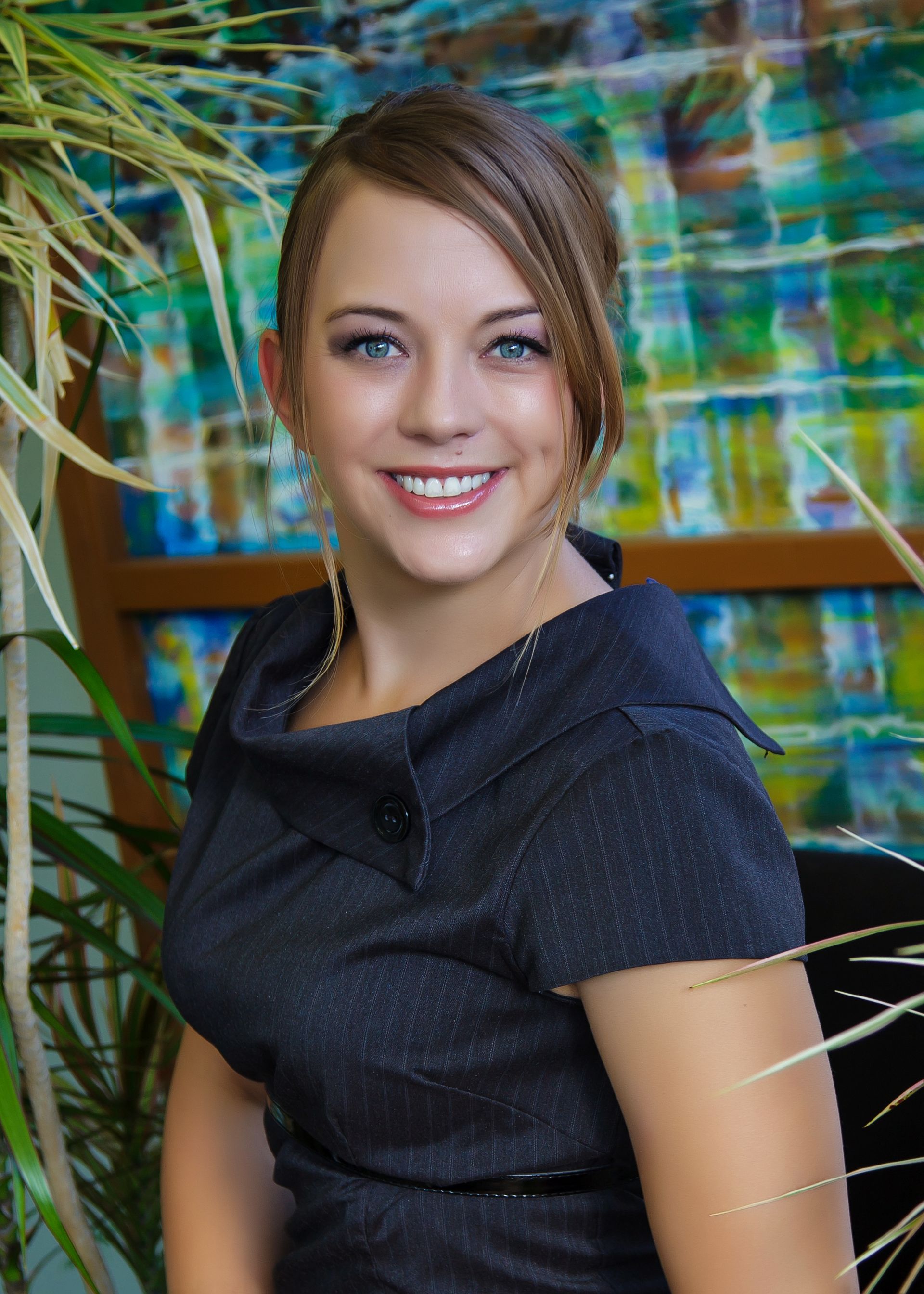 Chelsea in a black dress is smiling in front of a painting