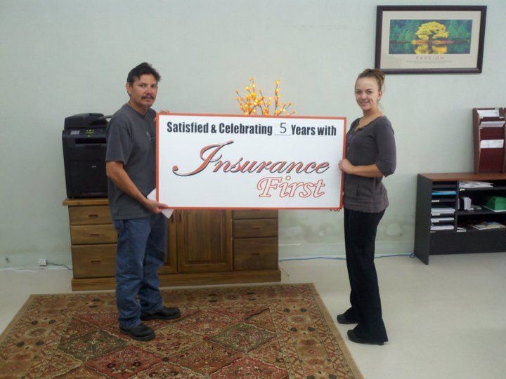 A man and a woman holding a sign that says Insurance First