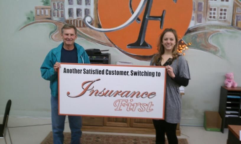 A man and a woman holding a sign that says Insurance First