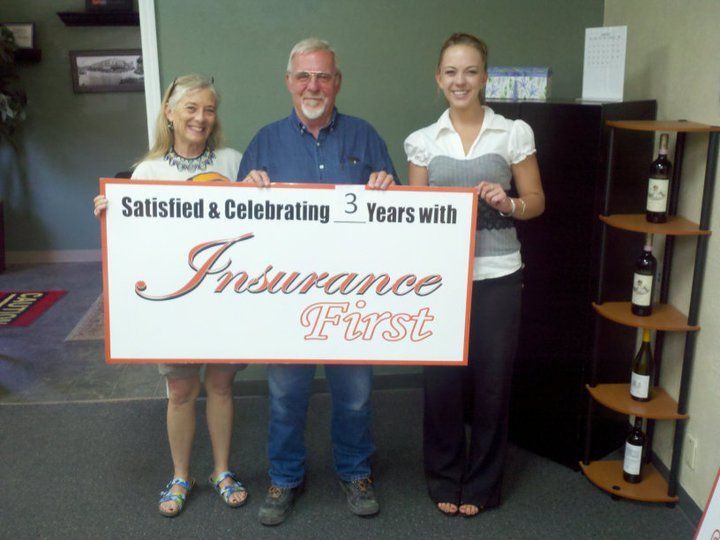 Three people holding a sign that says satisfied and celebrating 3 years with Insurance First