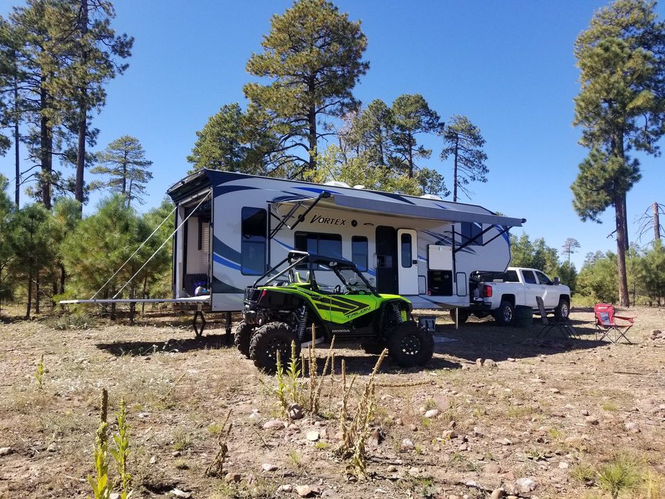 A green atv is parked in front of a trailer.