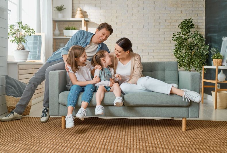 A family is sitting on a couch in a living room.