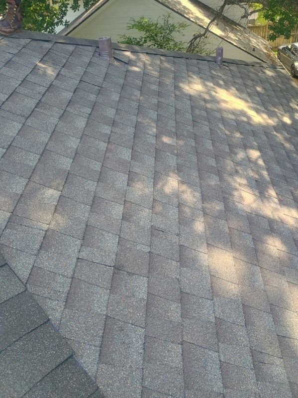 Gray shingle roof with tree shadows and a triangular dormer window at the top.