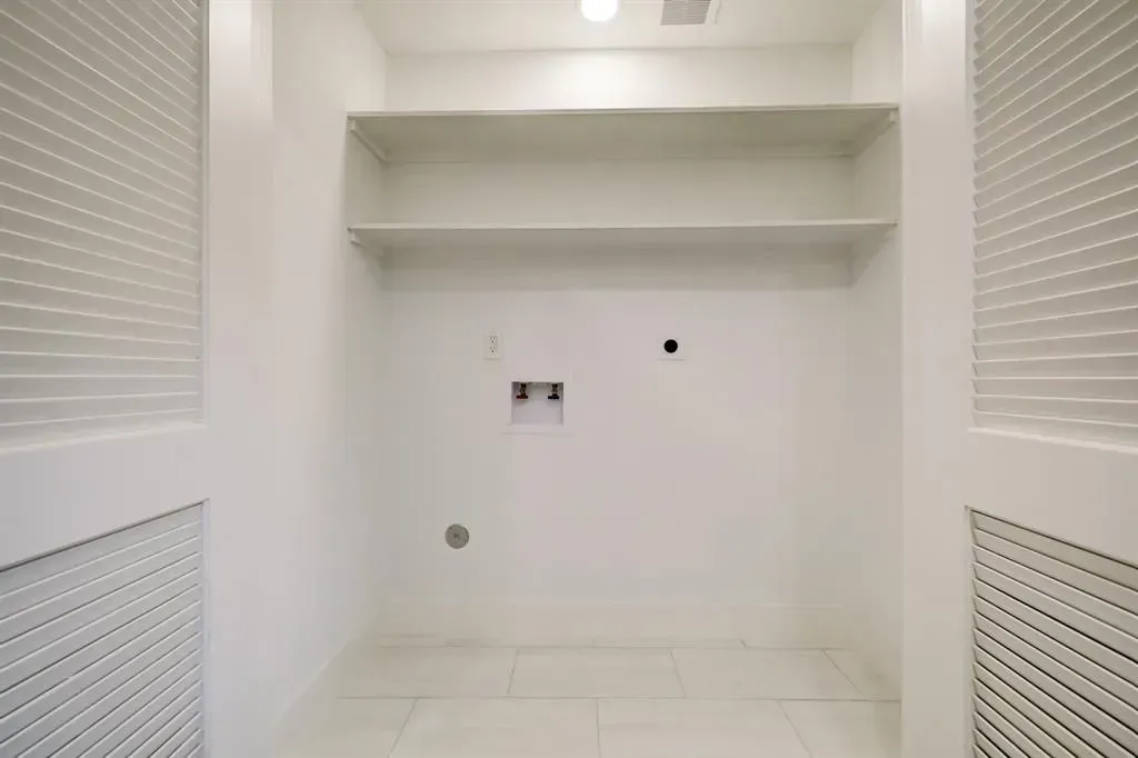 Empty white walk-in closet with built-in shelves and louvered doors.