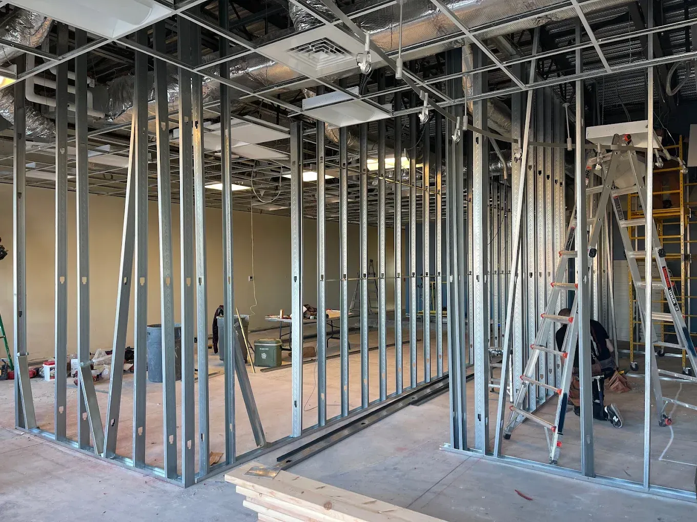 Interior of a room under construction, with metal studs framing walls, ceilings, and an open area.