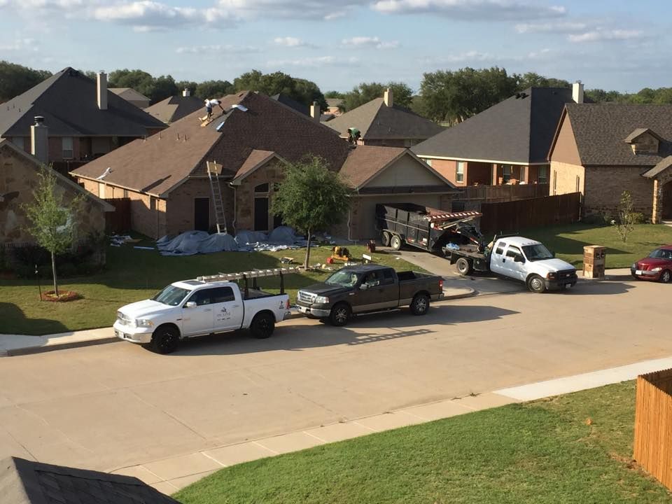 Gray metal roof on a house with a gutter and chimney, set against green trees.