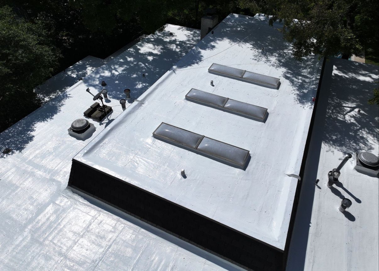 Flat white roof with three skylights, two vents, and dark trim.