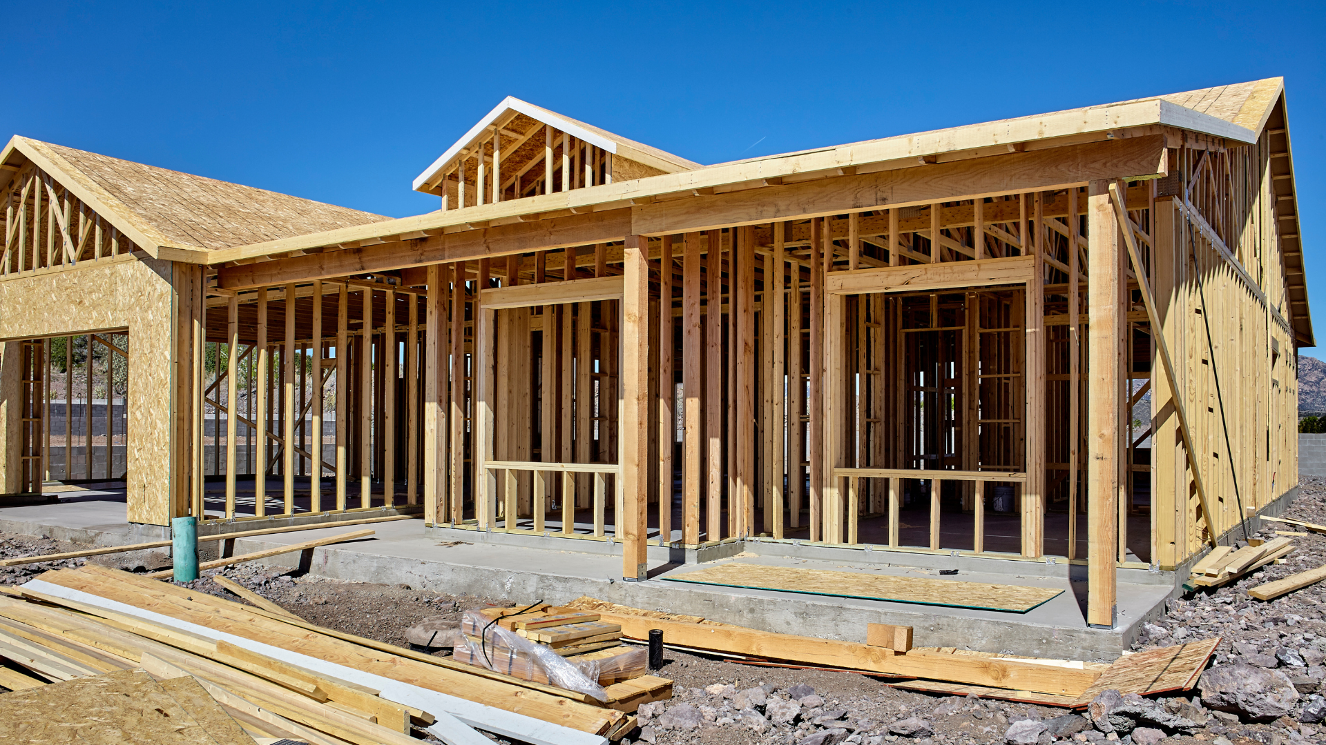 House under construction: Wooden frame against a clear blue sky.