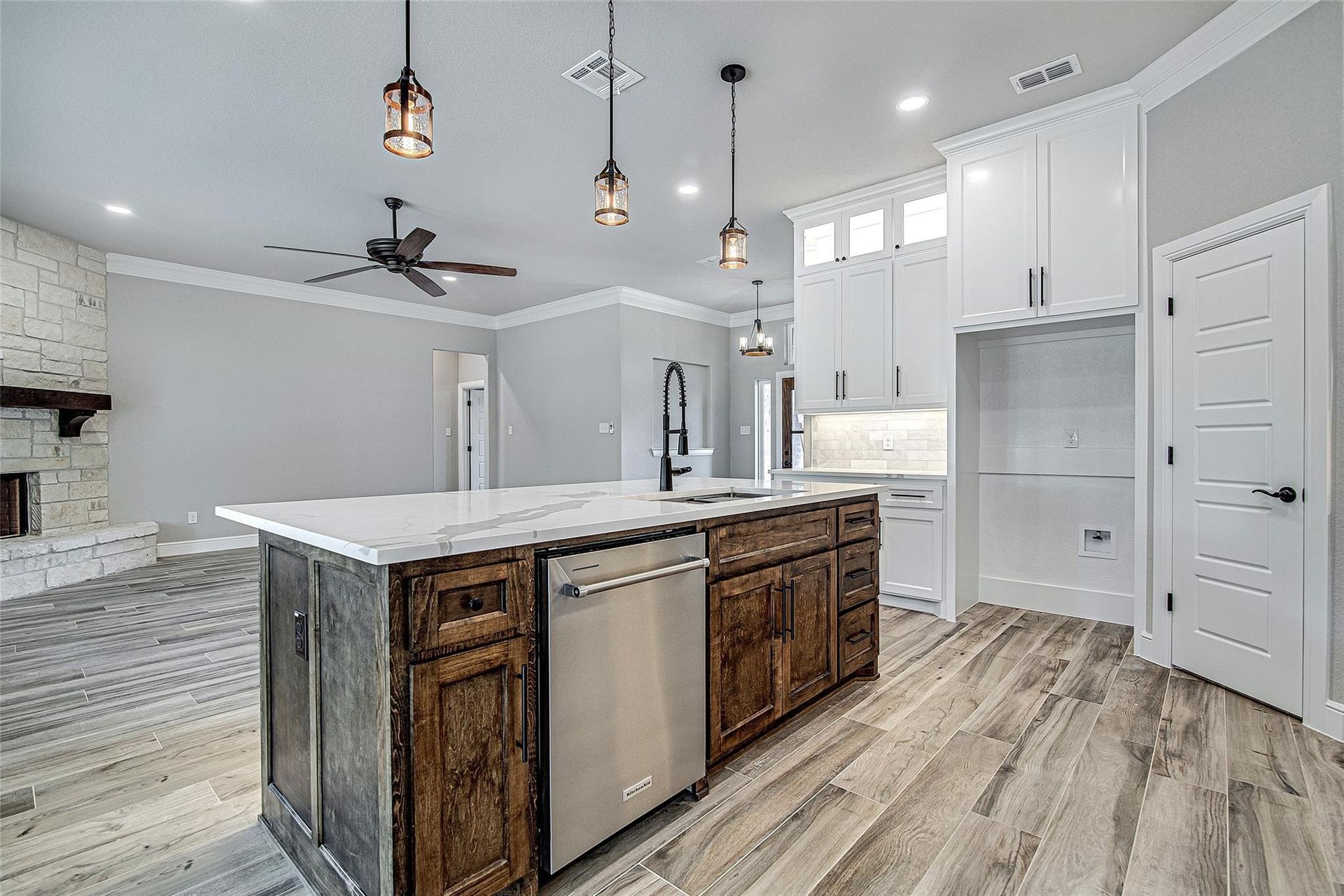 Bright white kitchen with stainless steel appliances, island, and overhead track lighting.