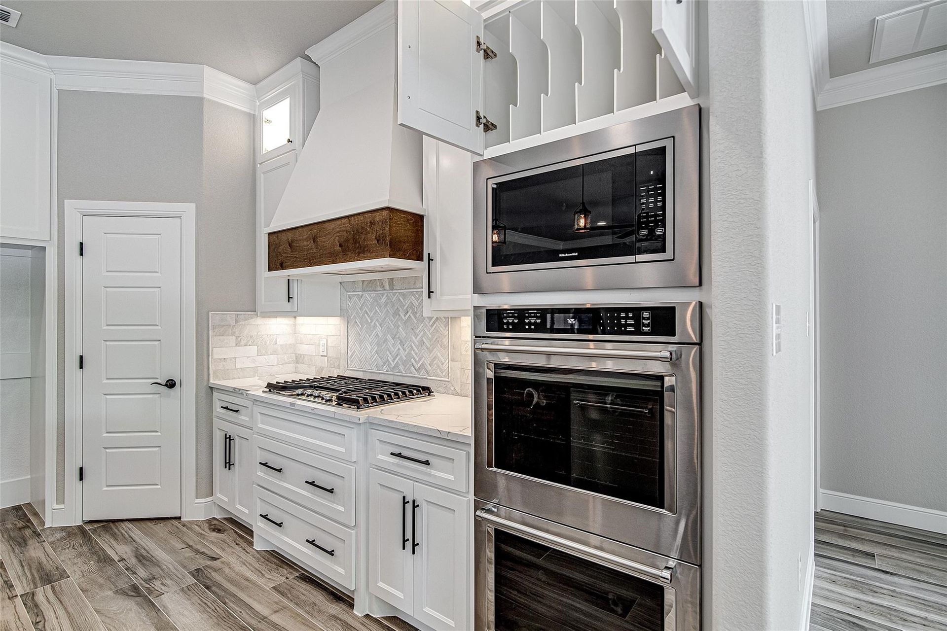 Modern kitchen with dark wood cabinets, marble island, stainless steel appliances, and bar stools.