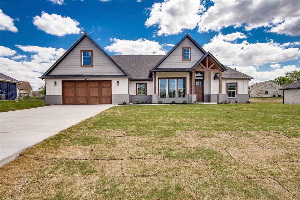 Tan house with brown shingled roof, white trim, and blue window reflections.