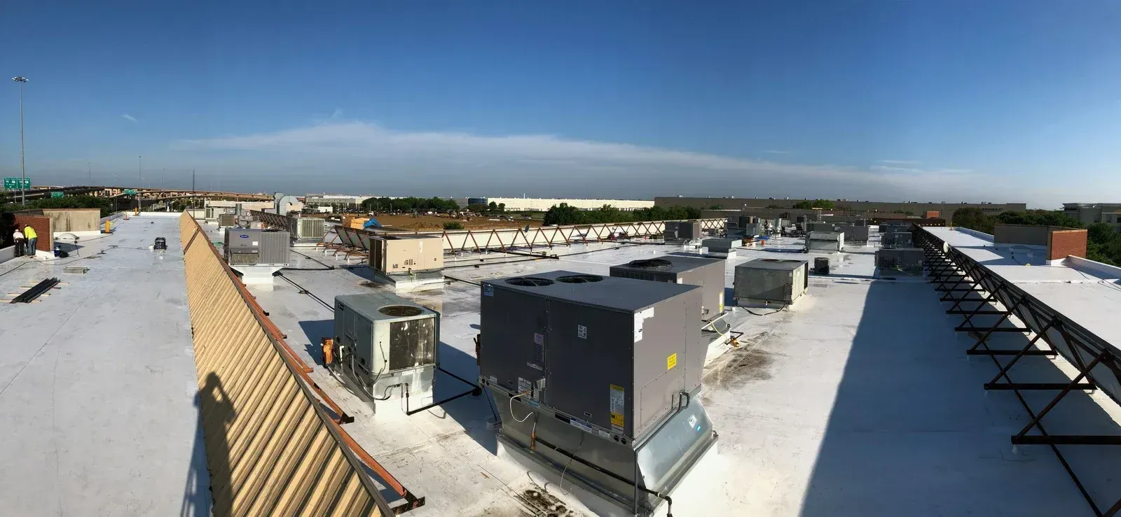 Rooftop view of commercial buildings with HVAC units and a blue sky.