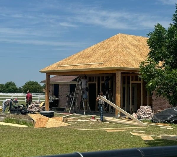 Construction workers building a house addition on a sunny day.