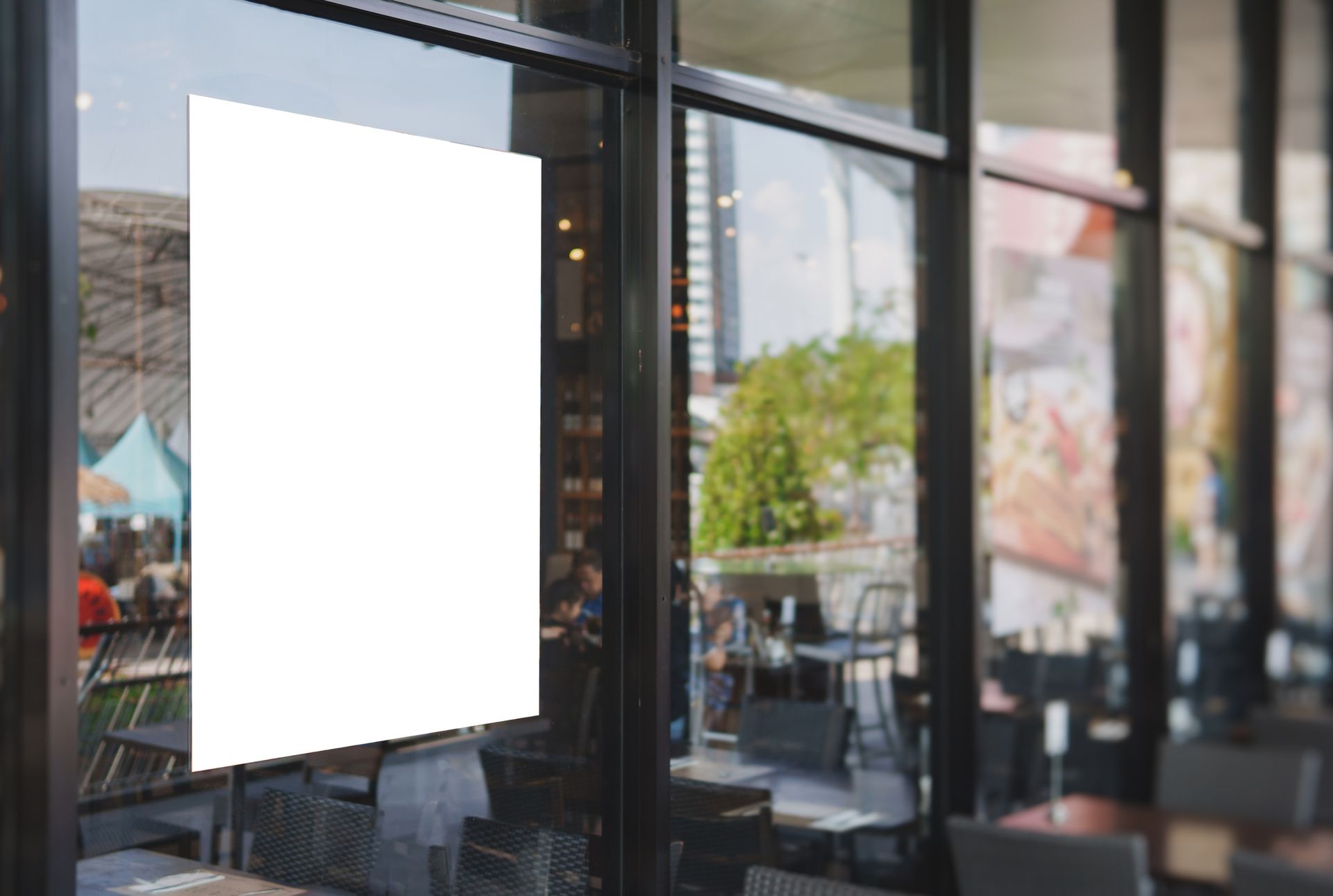 A white poster is hanging on a window in a restaurant.