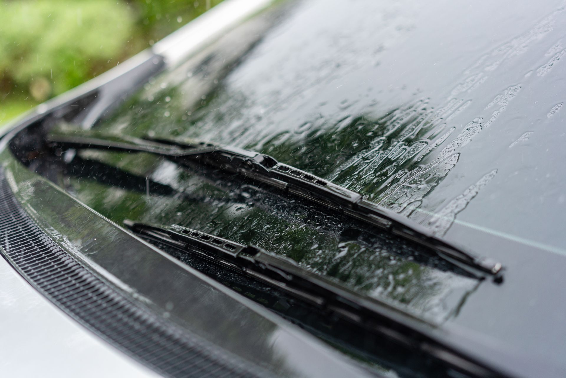 A close up of a car windshield with wiper blades on it.
