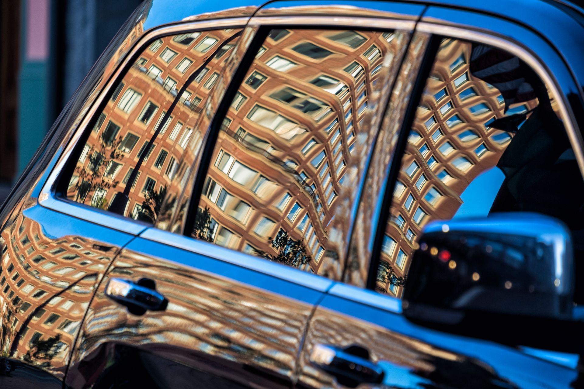 A car with a reflection of a building in the window