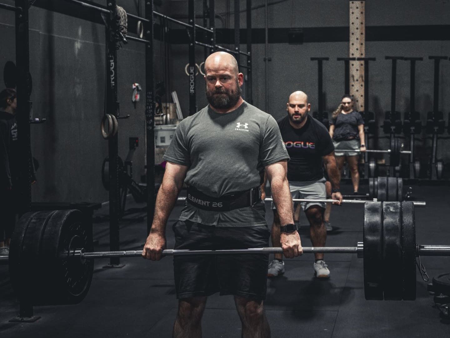 A group of men are lifting a barbell in a gym.