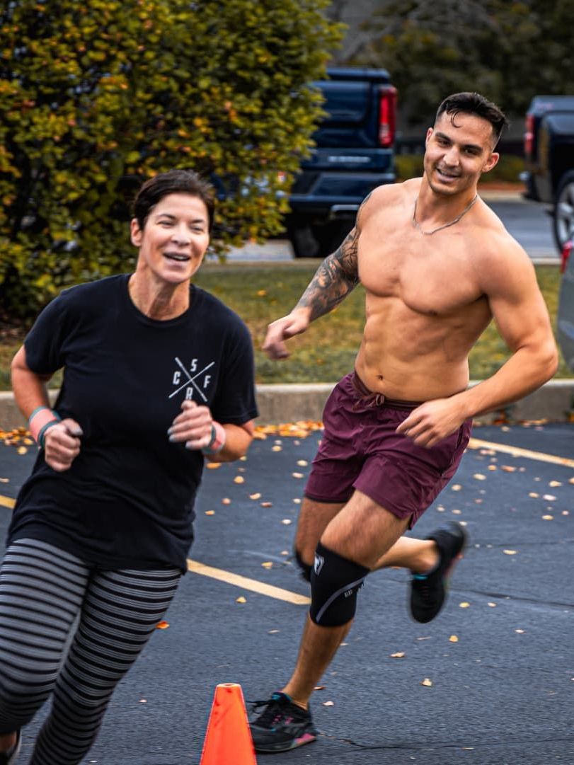 A man and a woman are running in a parking lot.