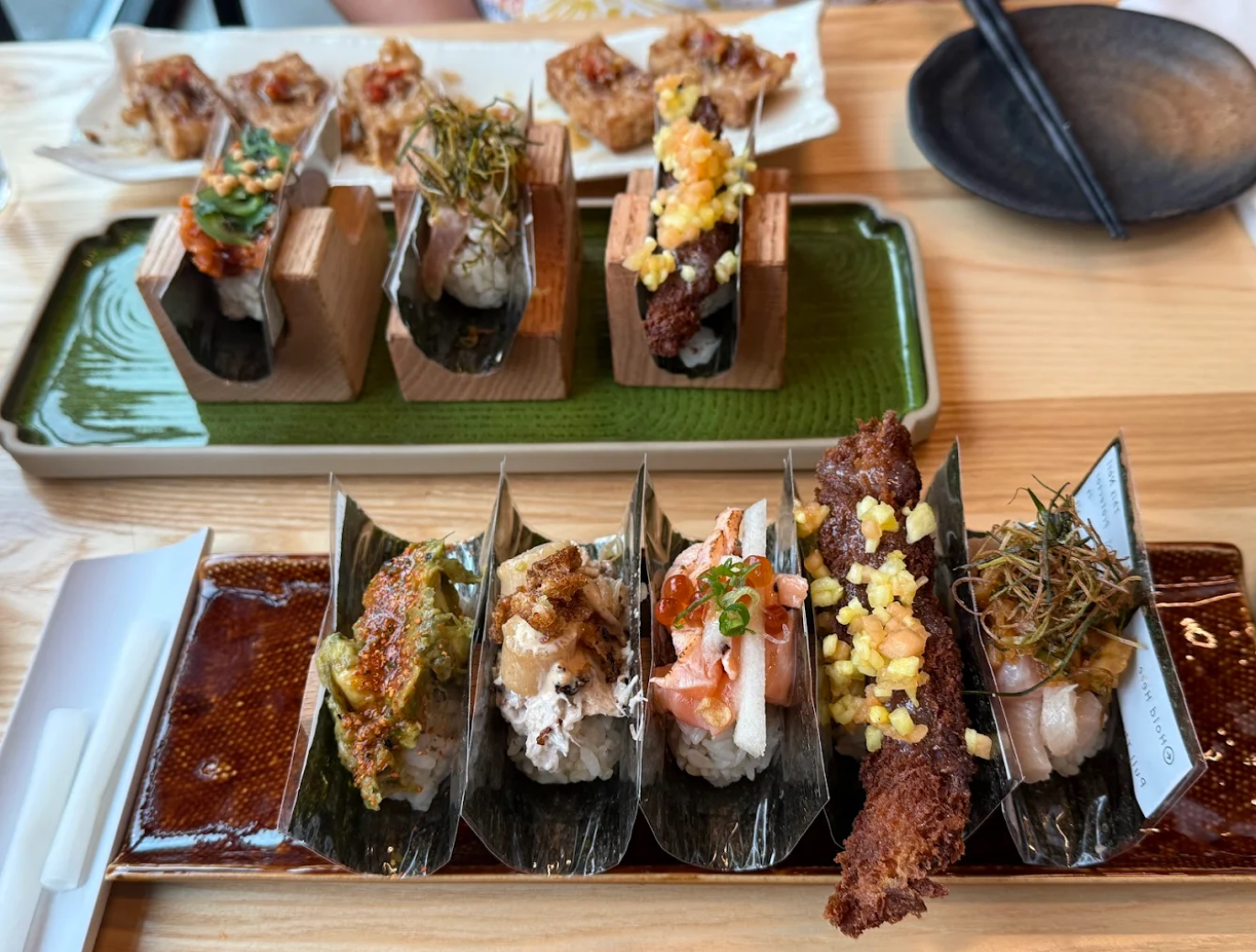 Sushi tacos on wooden stands and plates, with colorful toppings.