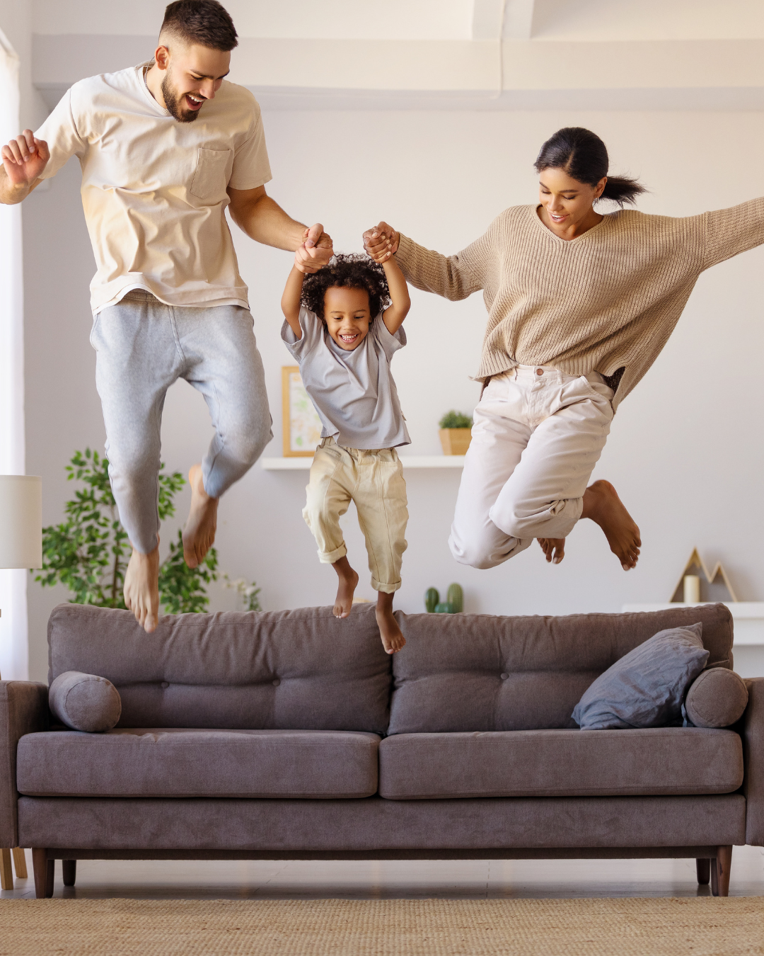 A family is jumping on a couch in a living room.