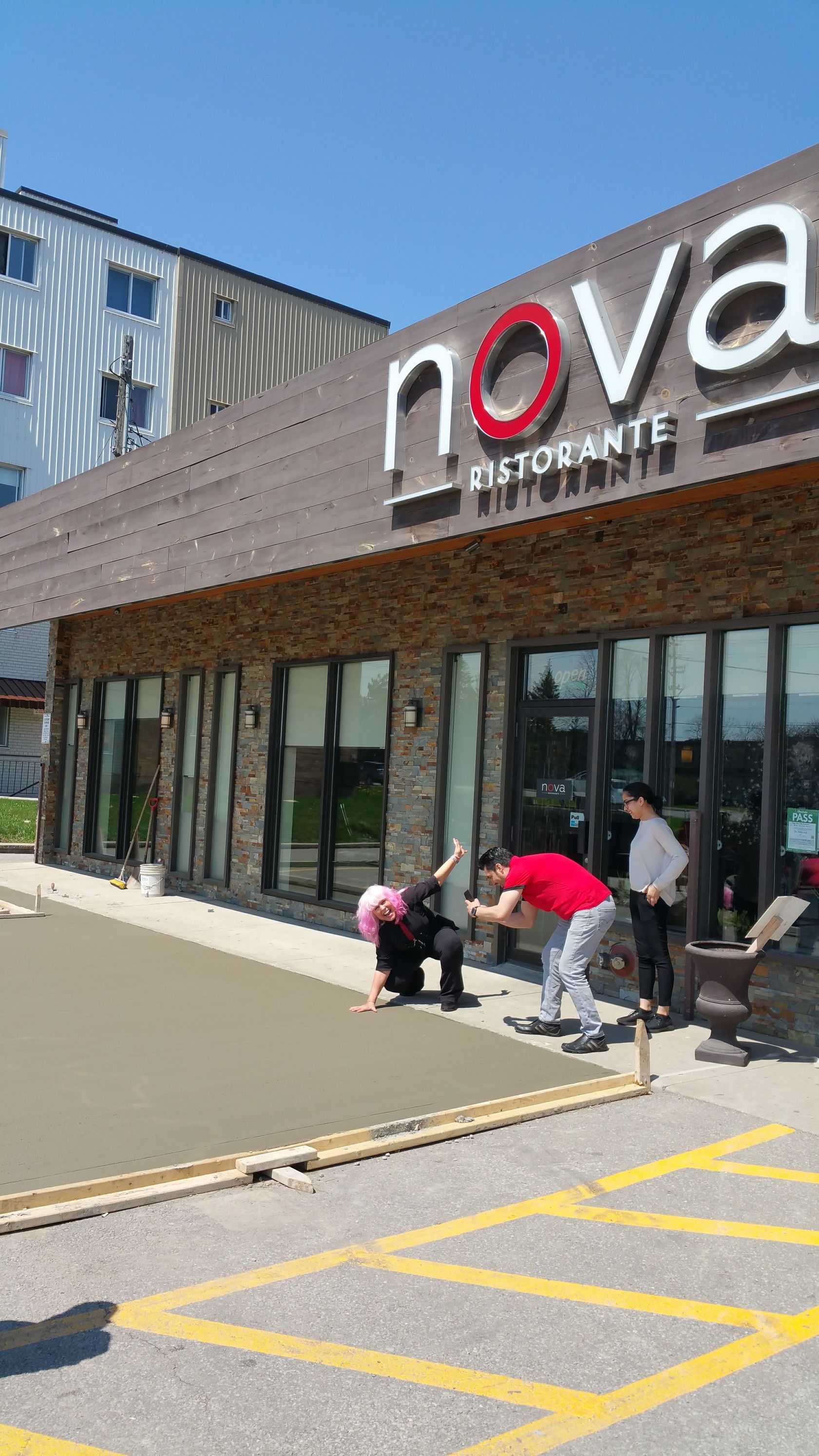 A group of people are working on a parking lot in front of a nova restaurant.