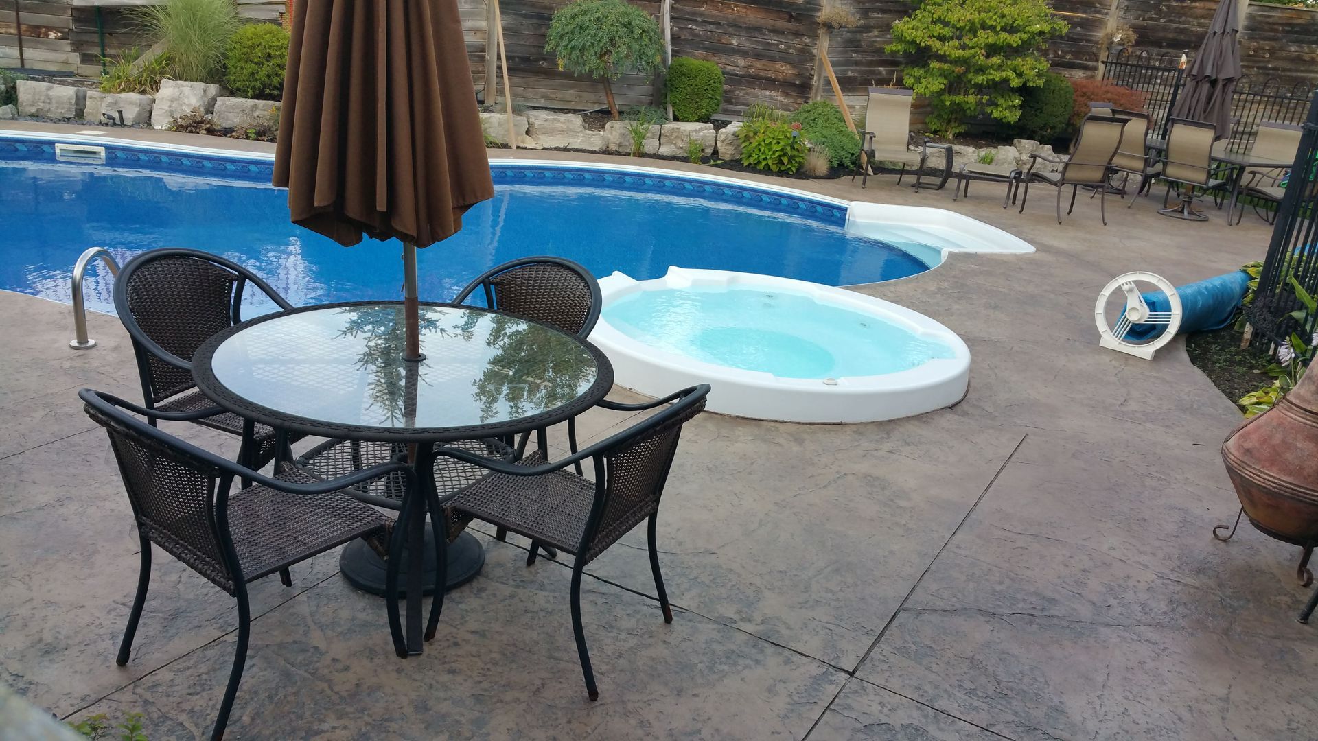 A table and chairs are sitting in front of a swimming pool.
