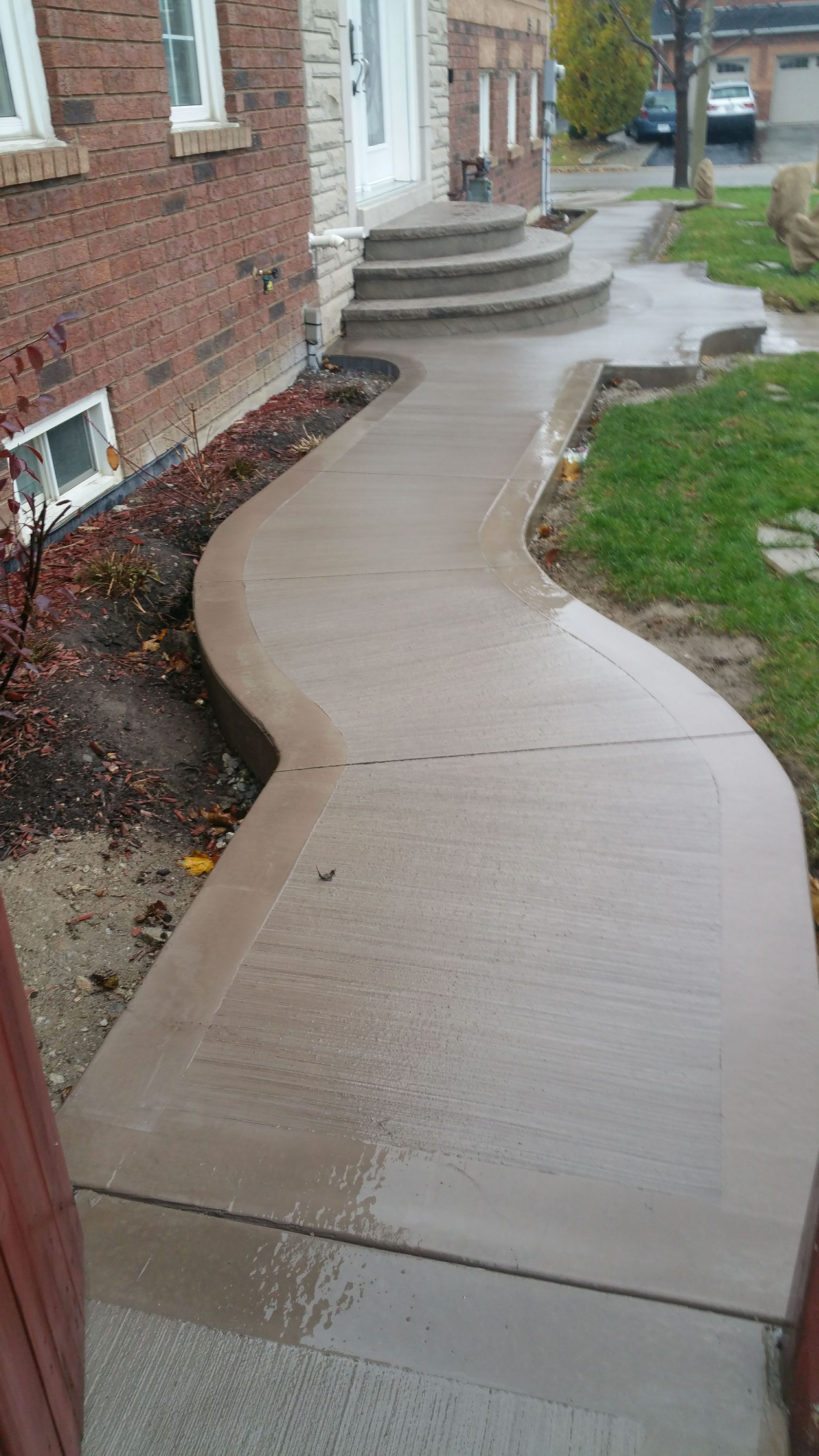A concrete walkway leading to the front door of a house.