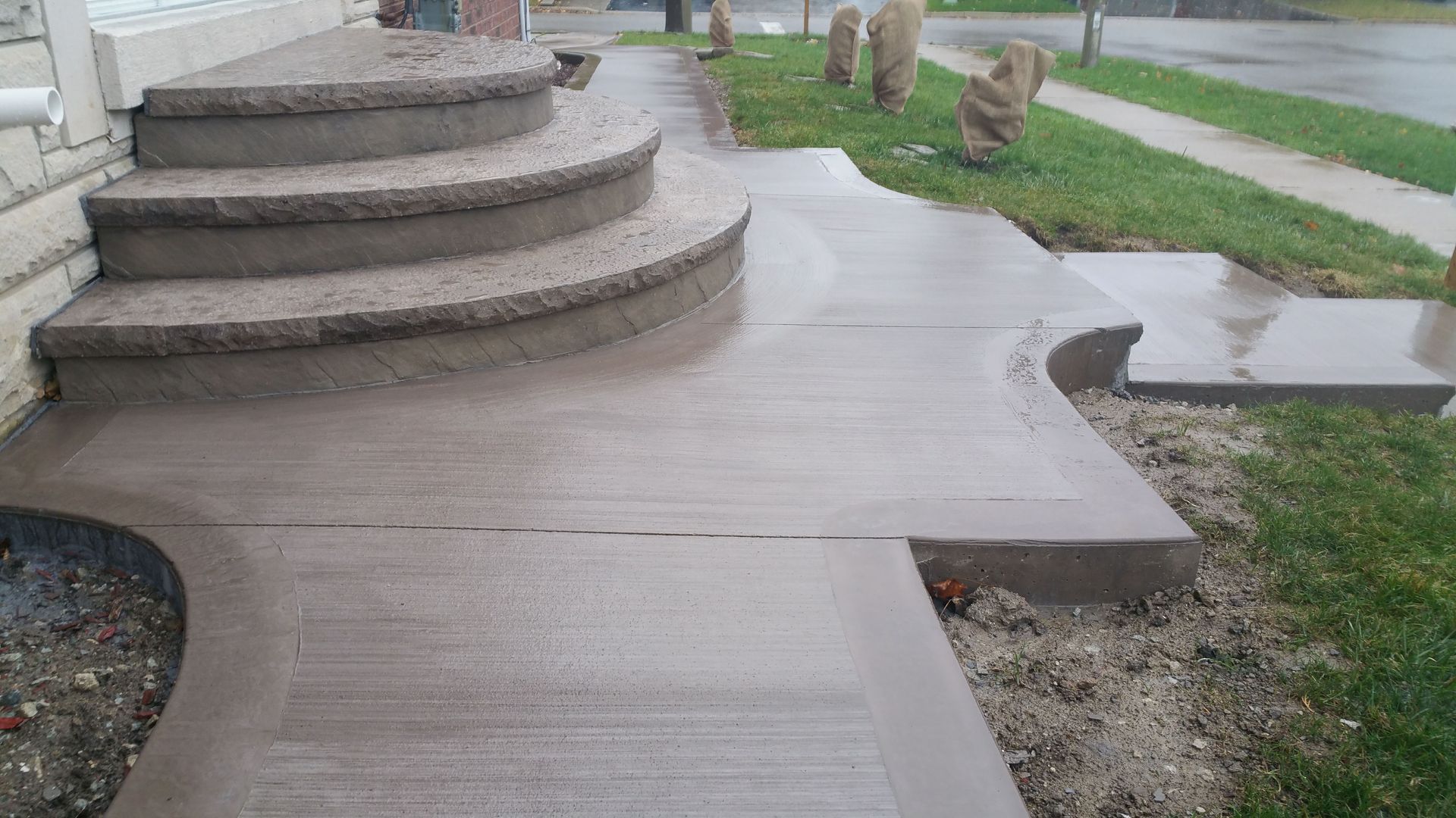 A concrete walkway with stairs leading up to a house.