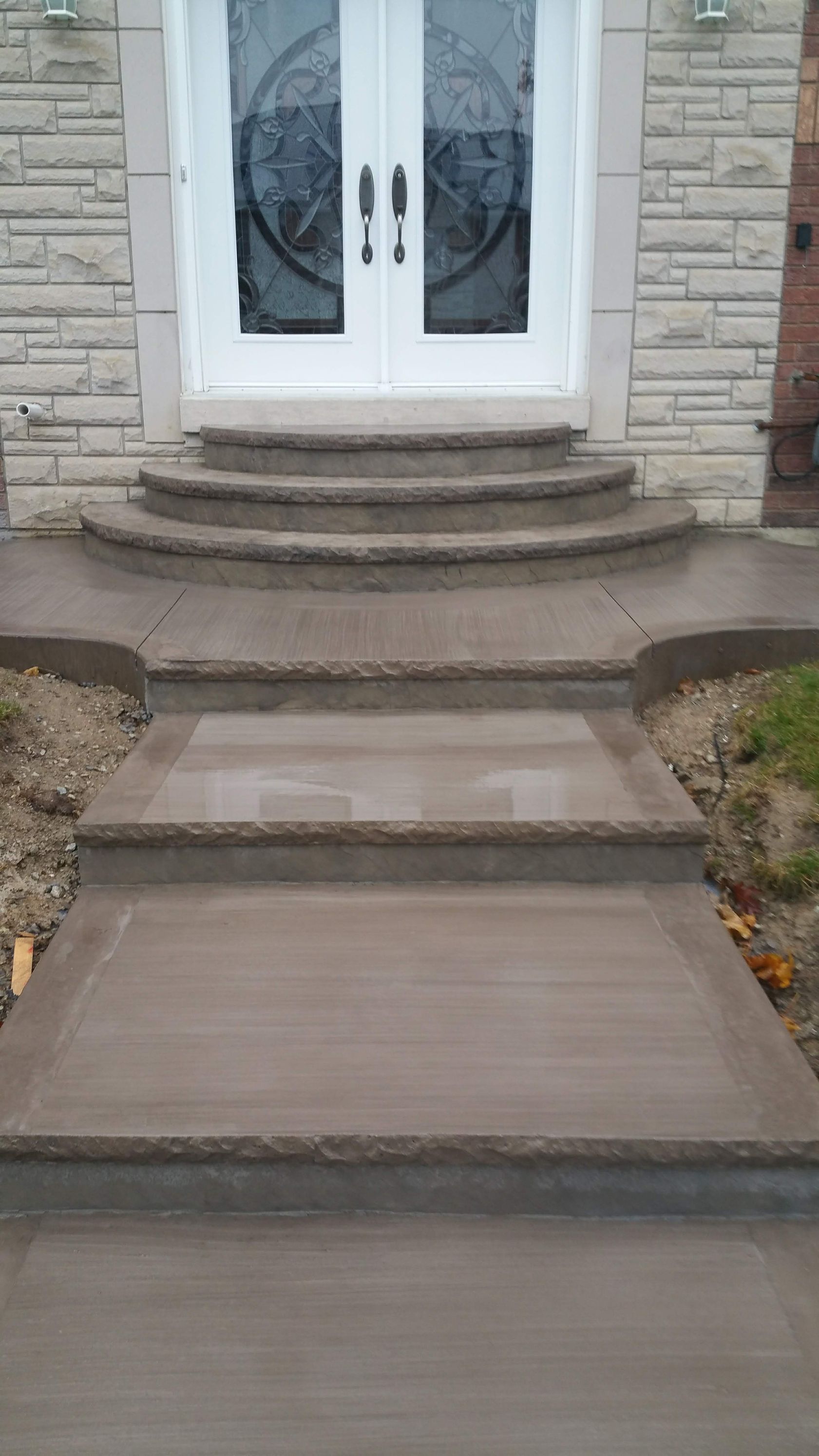A set of concrete steps leading up to the front door of a house.
