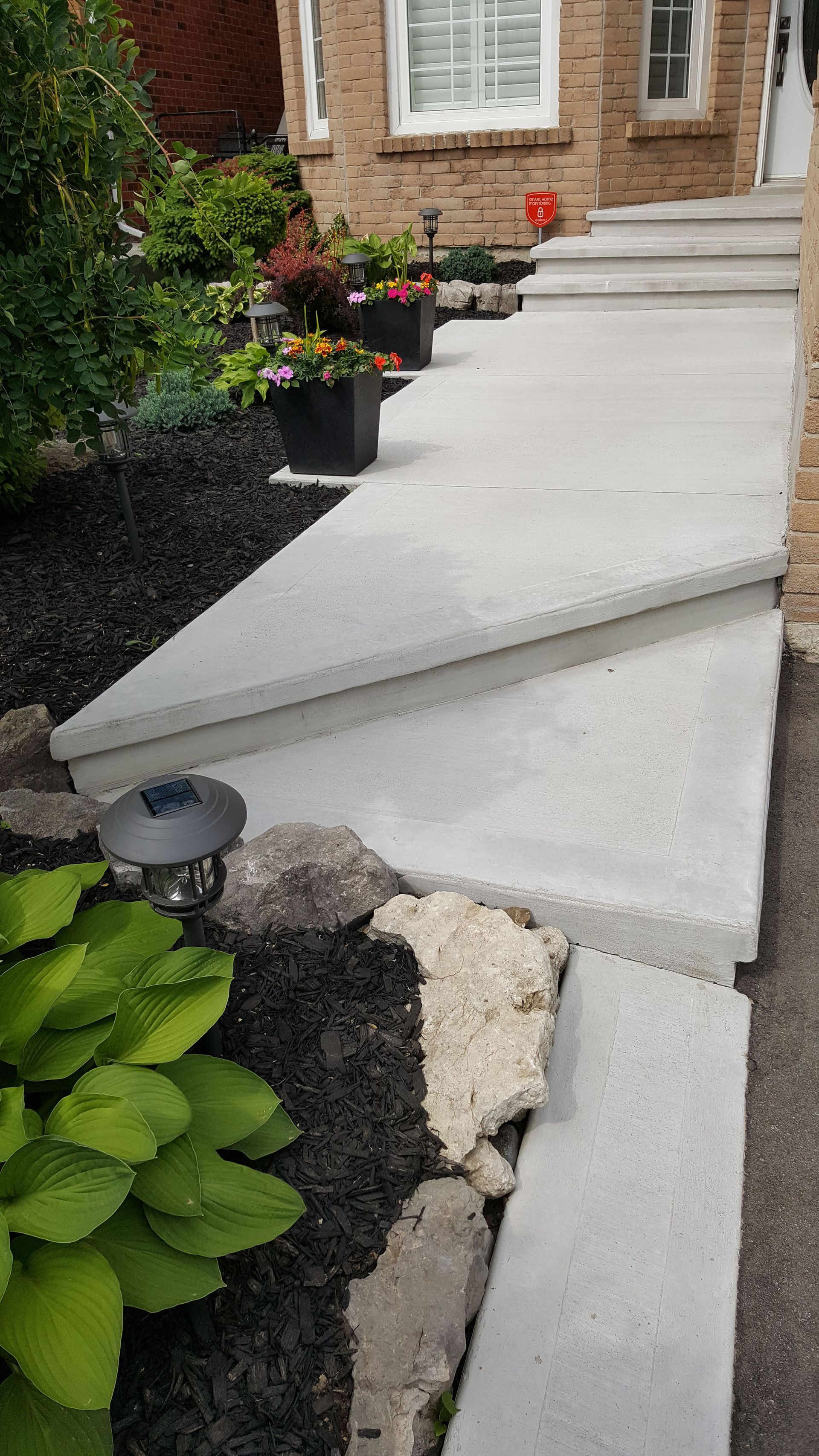 A concrete walkway with steps leading up to a house.