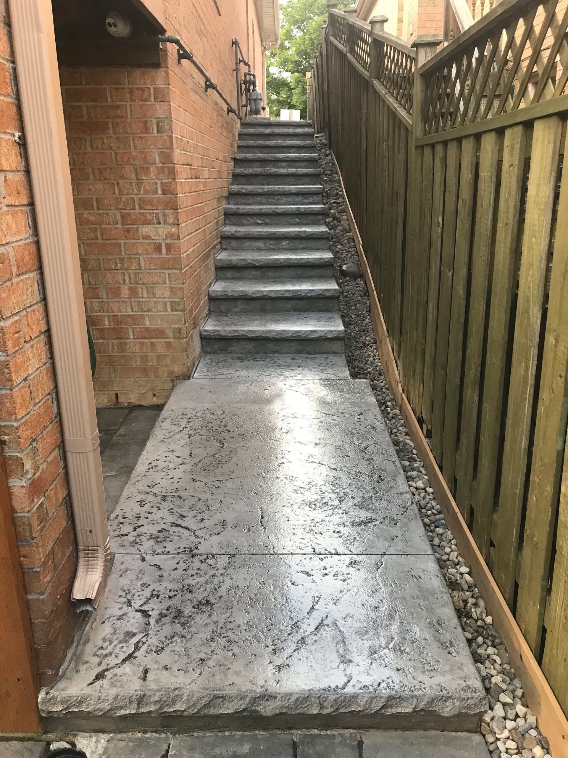 A set of stairs leading up to a brick building next to a wooden fence.