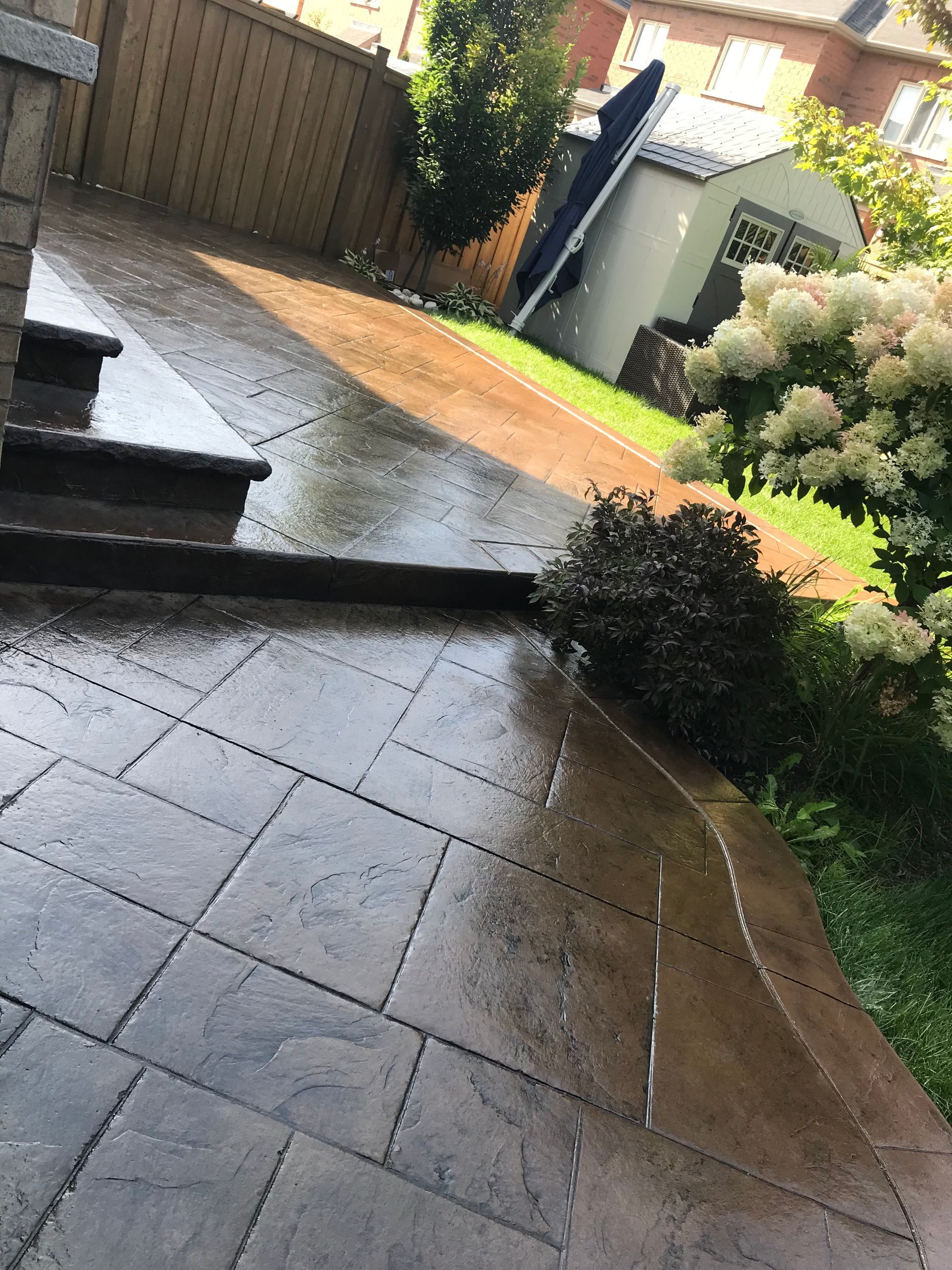 A patio with steps and a shed in the background