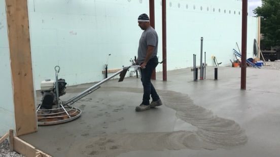 A man is working on a concrete floor with a machine.