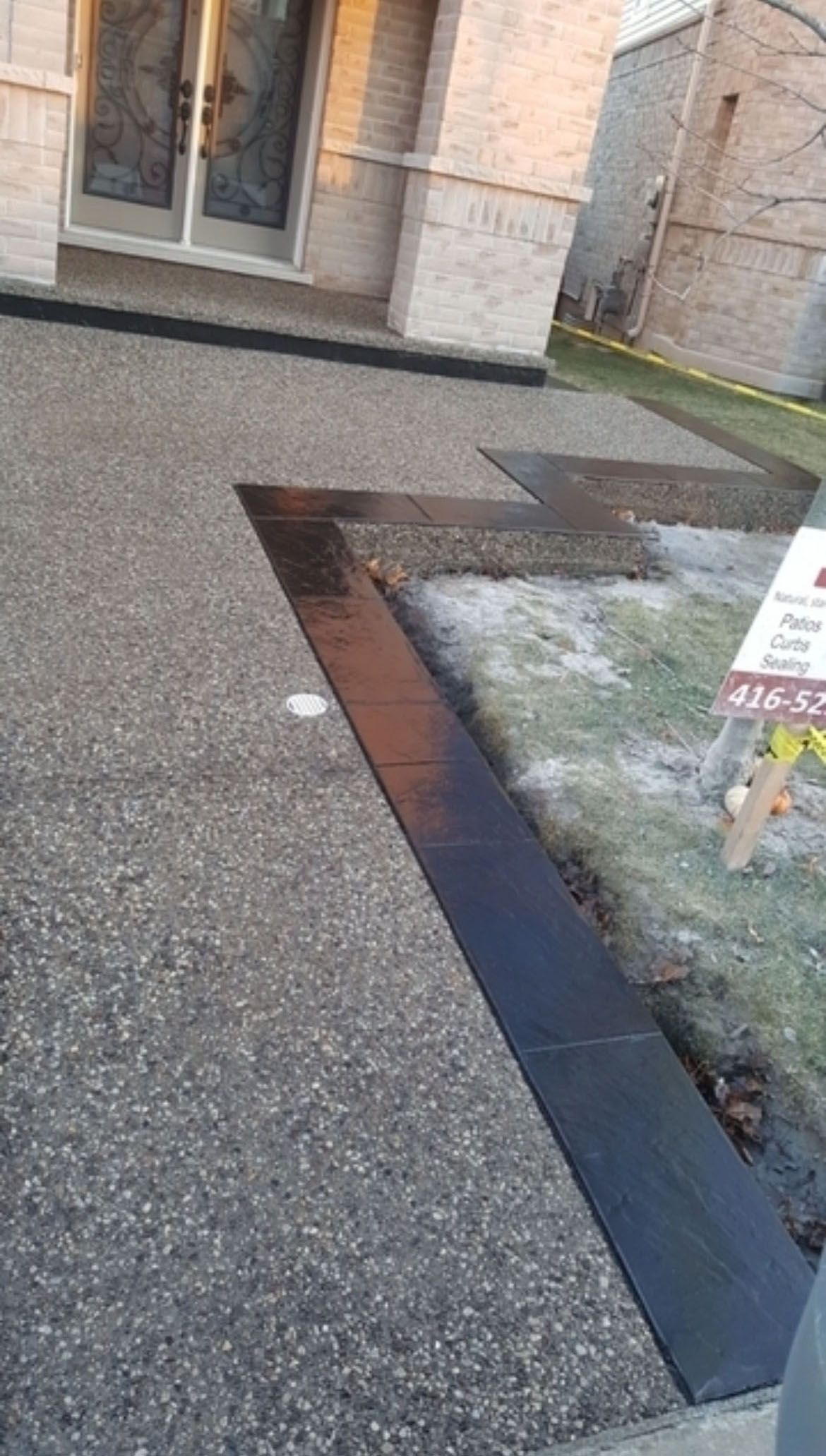 A concrete driveway in front of a house with a for sale sign.