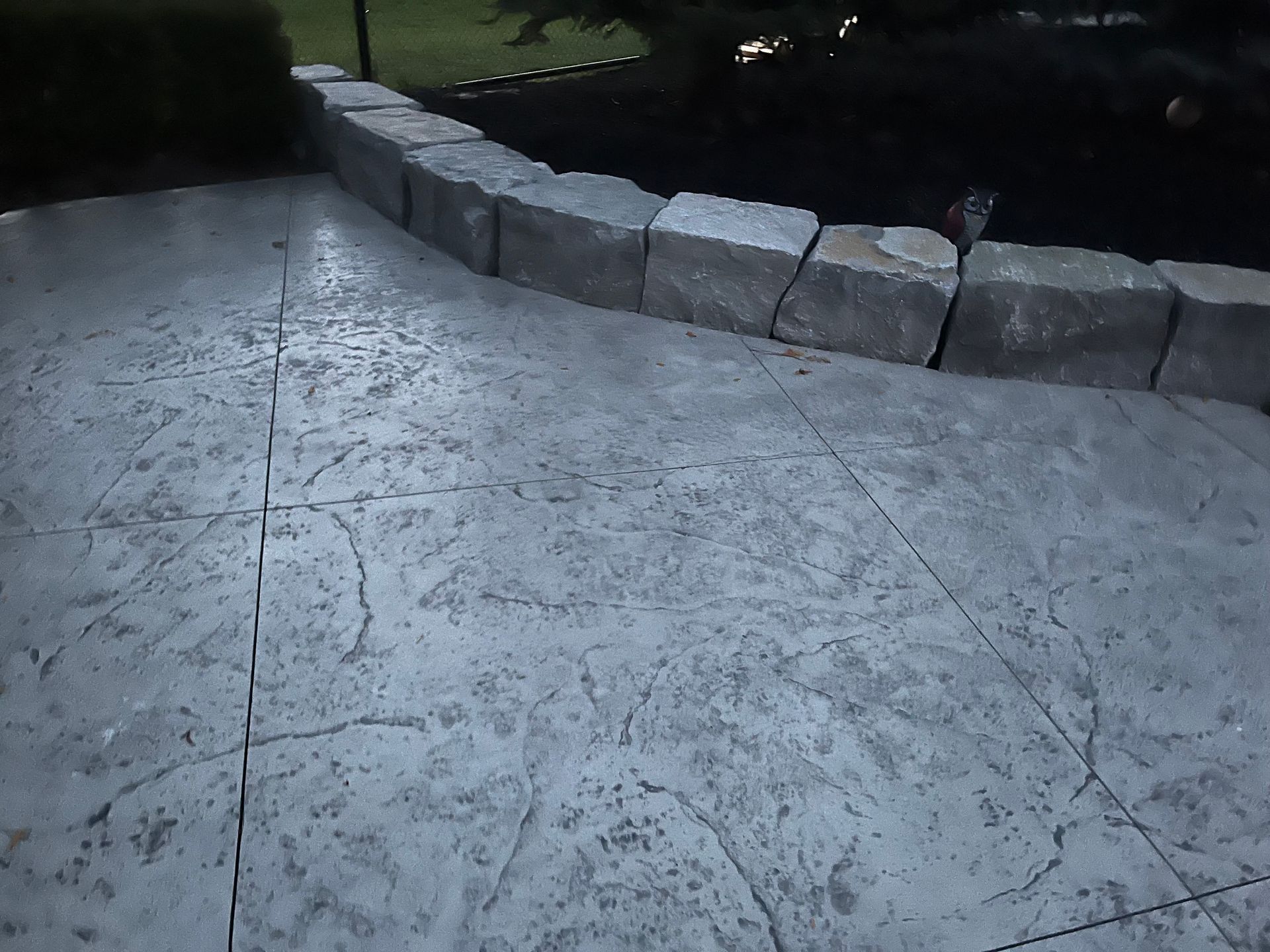 A concrete walkway with a stone wall in the background