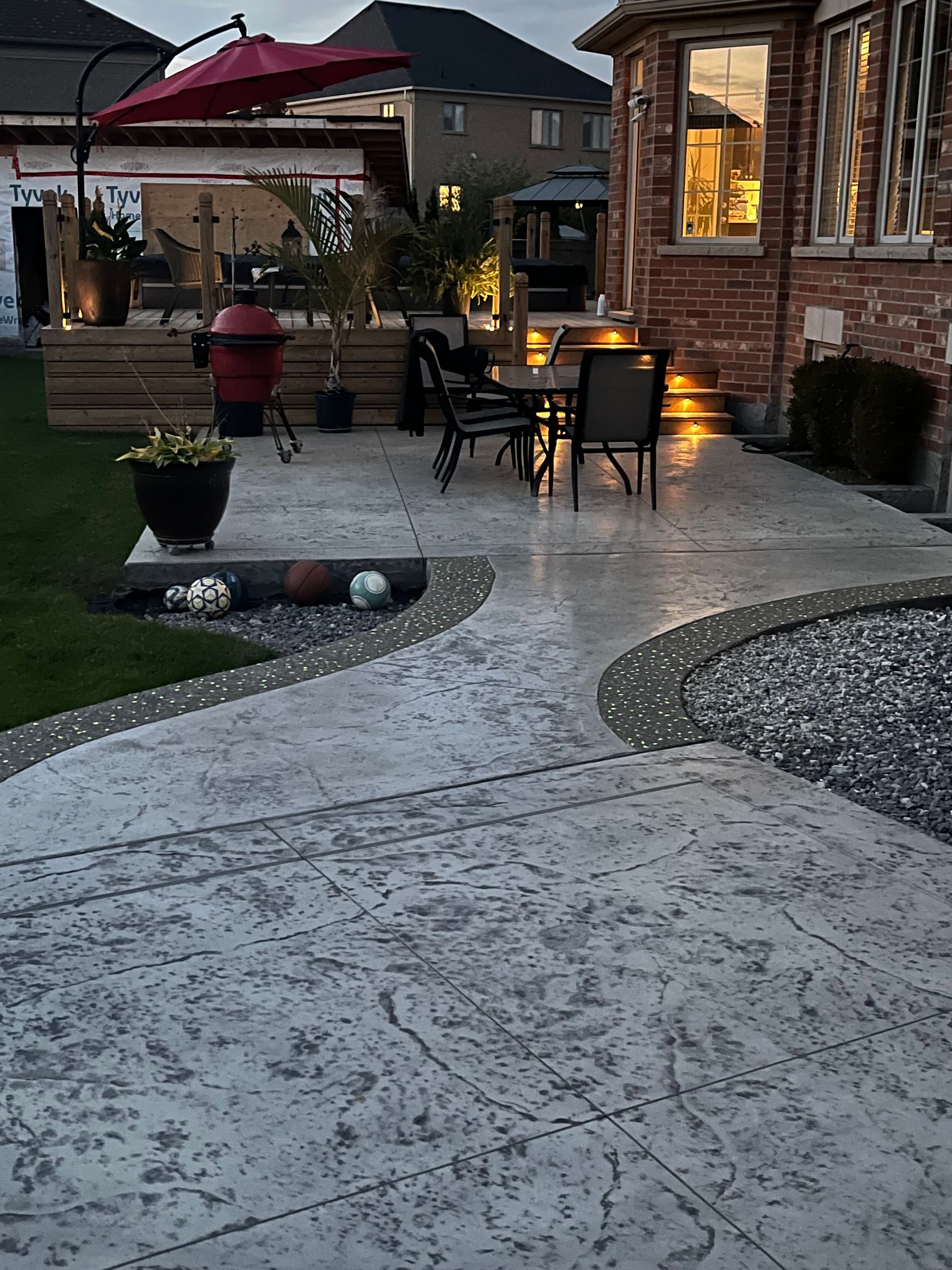 A patio with a table and chairs and an umbrella in front of a house.