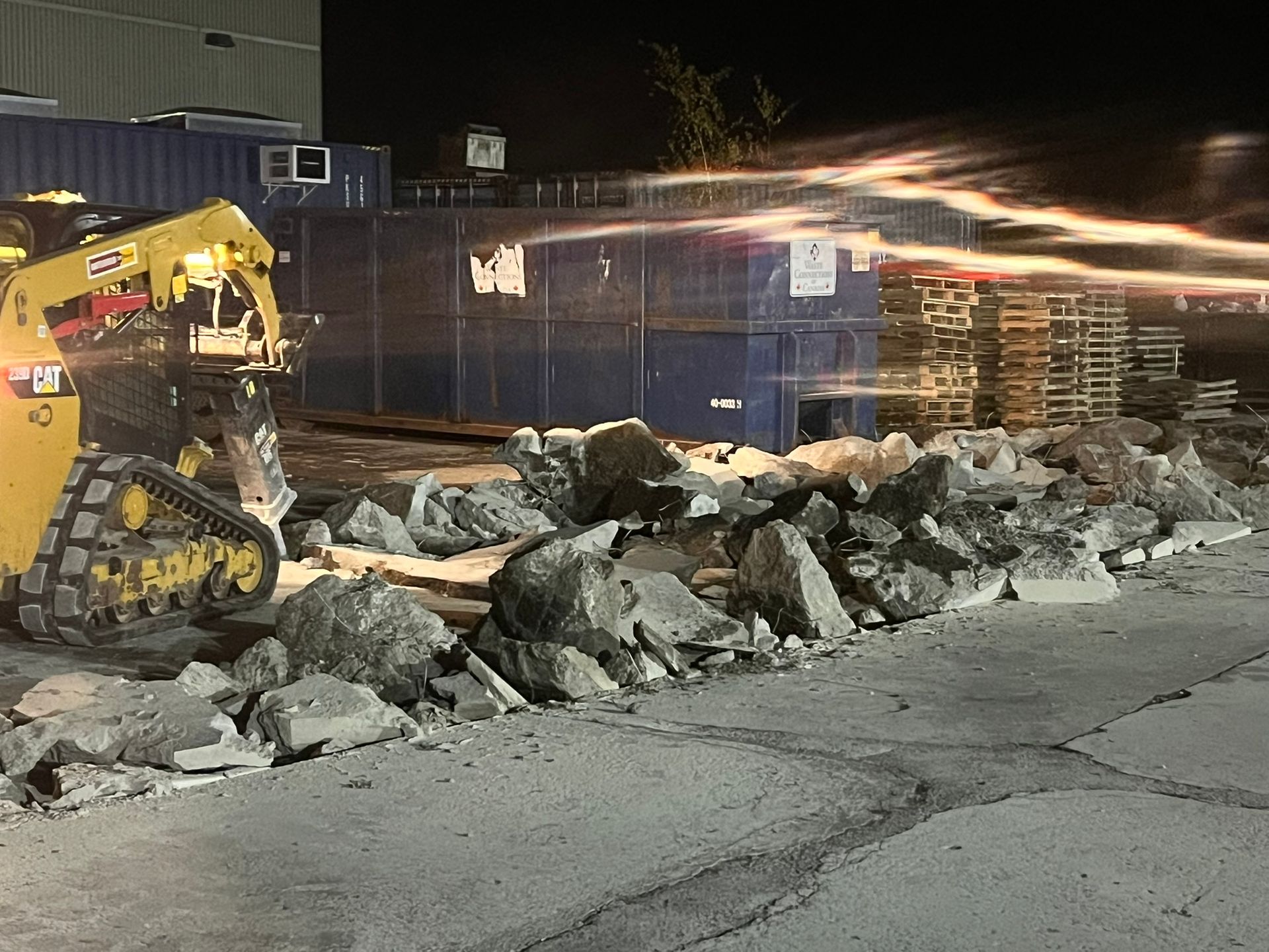 A bulldozer is moving rocks on a construction site at night.