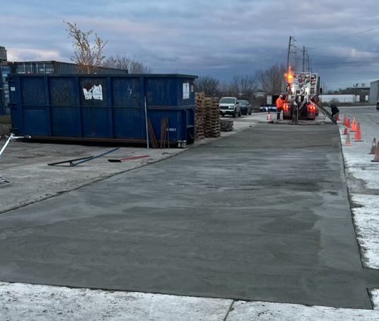 A large blue dumpster is sitting in the middle of a parking lot.