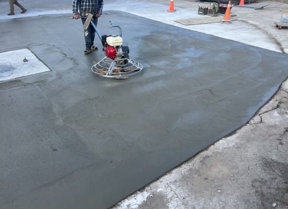 A man is using a machine to finish a concrete driveway