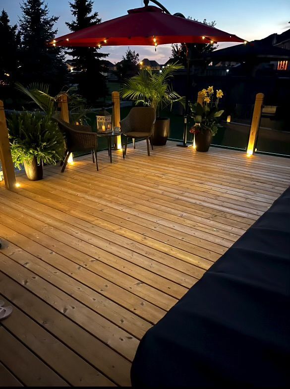 A wooden deck with a red umbrella and chairs