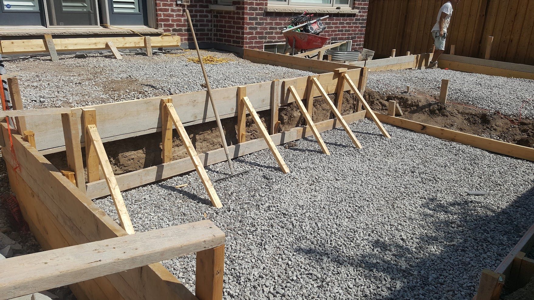 A row of wooden barriers are sitting on top of gravel in front of a brick house.