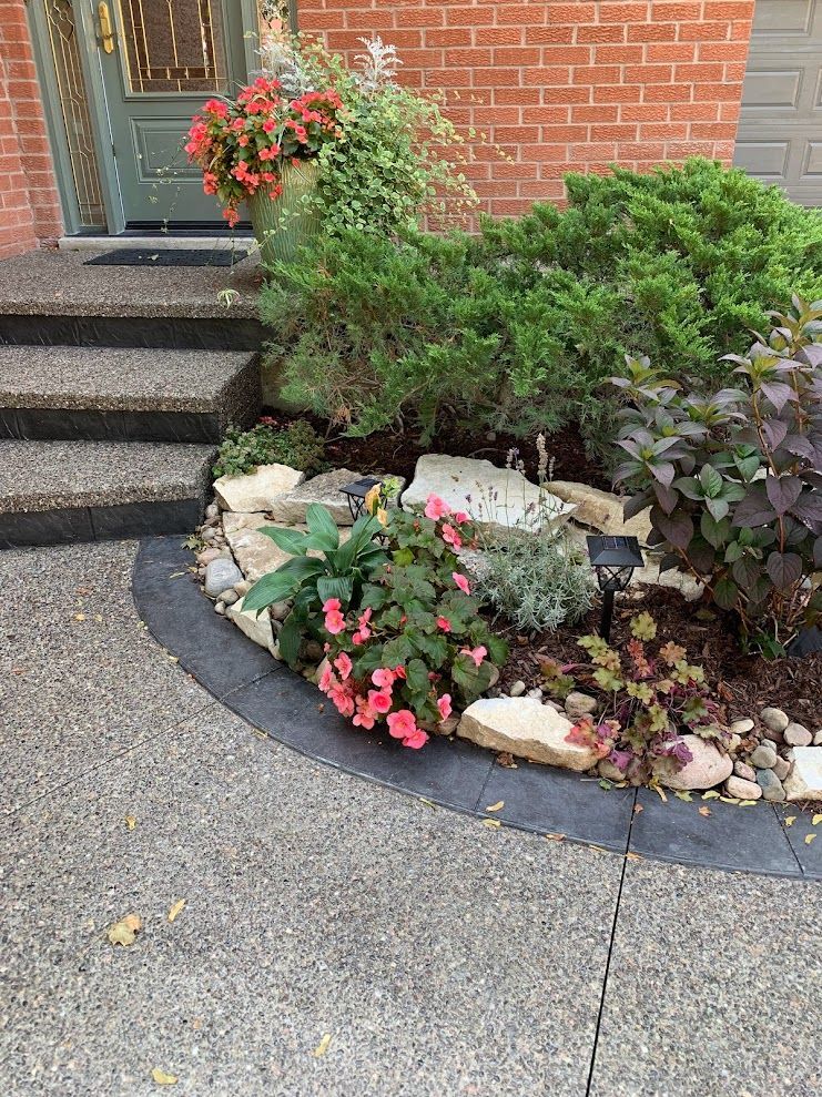 A garden with flowers and rocks in front of a brick house.