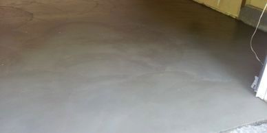 A concrete floor in a garage with a door in the background.