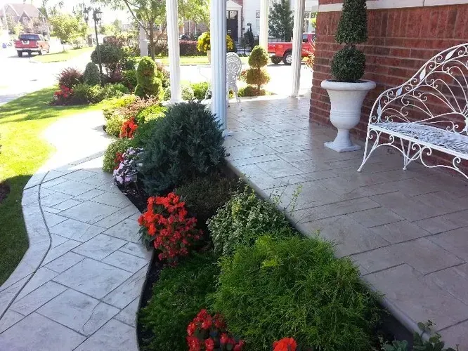 A white bench sits on a porch next to a garden