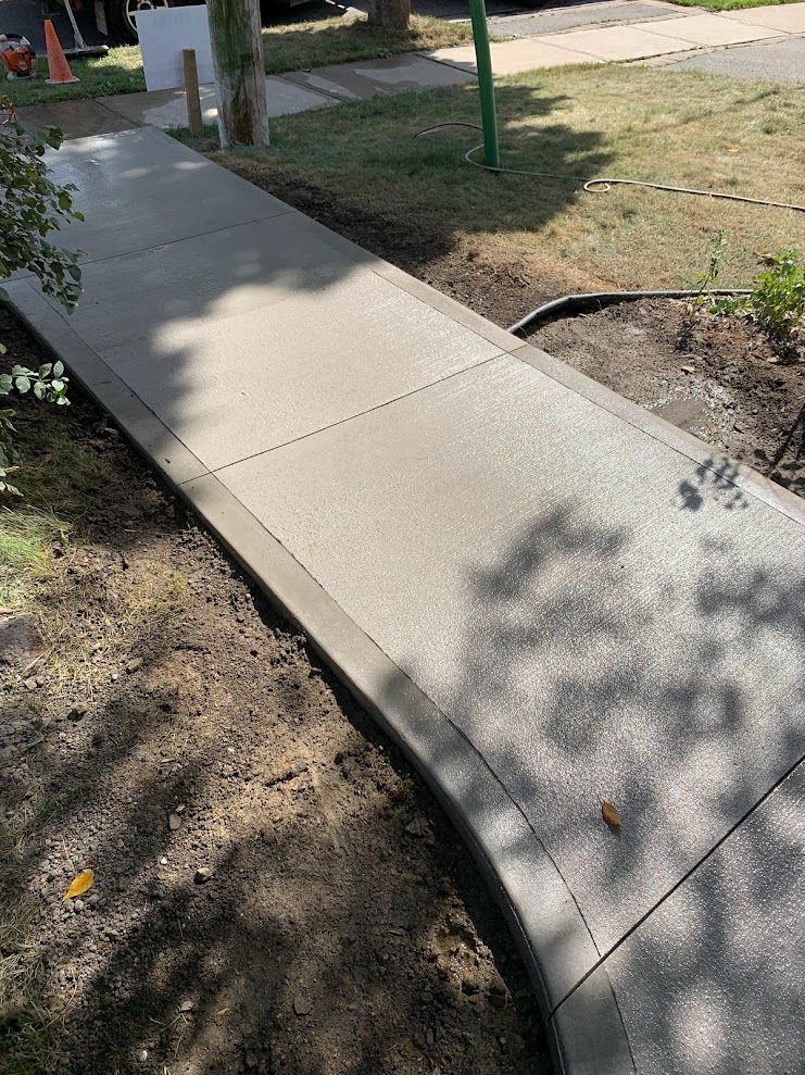 A concrete sidewalk is being built on the side of a road.