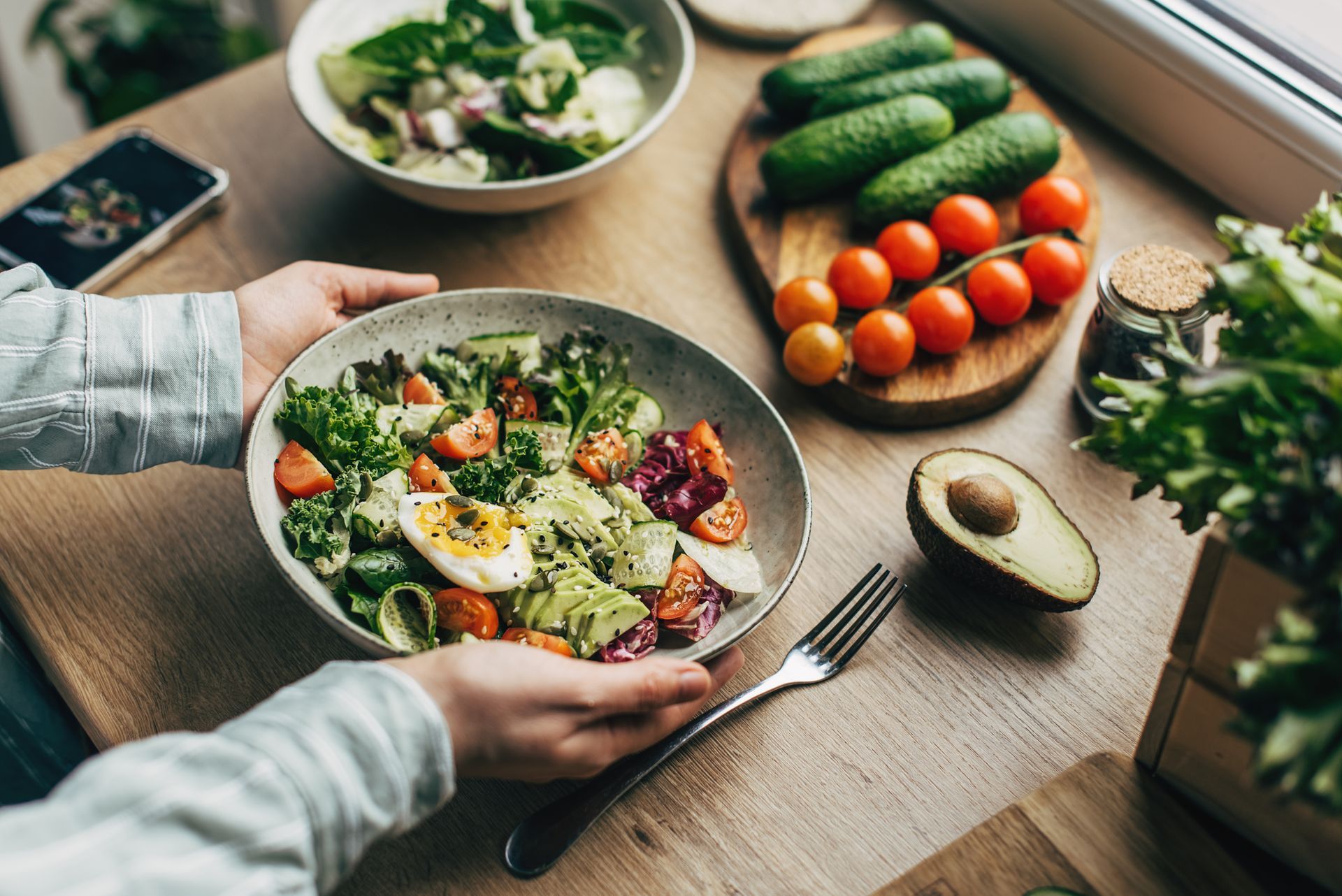 A person is eating a salad from a bowl on a table